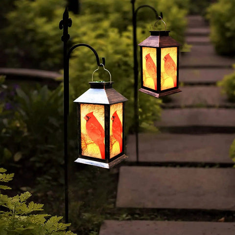 Outdoor Solar Lanterns For Hanging And Tabletop Use Waterproof LED Red Cardinal Bird Pattern Lights With S Hook Ideal Patio Garden Decor And Thoughtful Gift For Mom Grandma Women hanging on hooks in a garden.