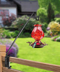 Heavy Duty 20 Inch Deck Hook With Swivel Wing Nut Design For Hummingbird Feeders holds a red feeder on a wood railing.