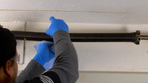 Person applying Silicone Garage Door Lubricant Spray For Smoother Quieter Operation On Tracks Rollers And Hinges Will Not Attract Dust Or Dirt Tack Free Formula Reduces Friction And Noise So Your Door Roars Less And Moves Smoothly 9.3 Oz Case Of 12 to overhead garage door spring