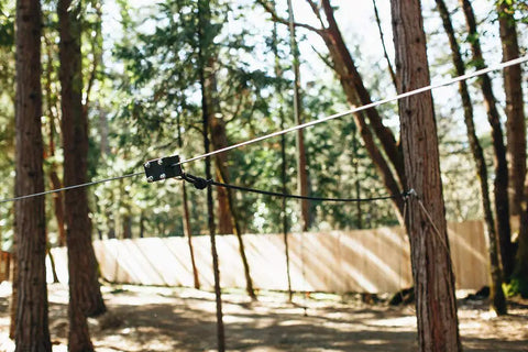 Backyard Zip Line Kit With Riding Gear, Heavy Duty 350 Pound Capacity, cable stretched between trees in wooded area