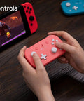 Hands holding Pocket Sized Lite 2 Bluetooth Controller With Motion Controls for Nintendo Switch On The Go, in pink color.