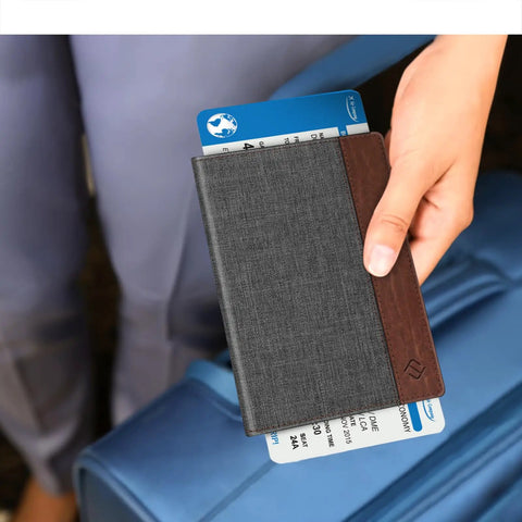 Slim RFID Blocking Passport Holder With Card Slots In Denim Charcoal Brown Your Go To Travel Wallet For Women And Men shown with blue luggage