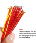 Hand holding red and yellow cables from 140 Piece Breadboard Jumper Wire Kit with 14 lengths of assorted color cables for dope prototyping.