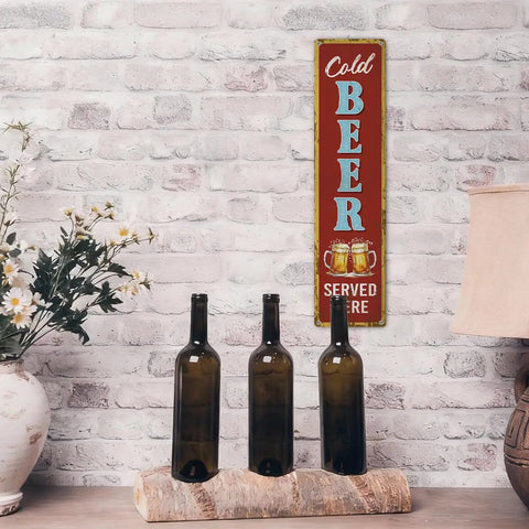 Rustic Cold Beer Served Here Metal Wall Sign Retro Vertical Tin Decor mounted on brick wall near brown bottles and lamp.