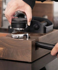 Person tamping coffee grounds using Wooden Espresso Knock Box And Tamper Holder Station With Non Slip Base Fits 58mm Portafilter.