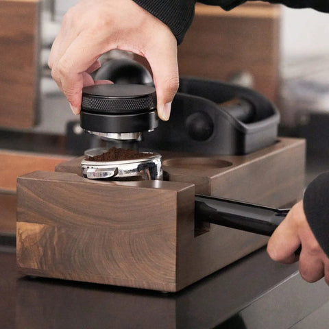 Person tamping coffee grounds using Wooden Espresso Knock Box And Tamper Holder Station With Non Slip Base Fits 58mm Portafilter.