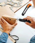 Person using 24 Pack Box Cutters With 18mm Snap Off Pro Grade Blades, Retractable Utility Knife Set for precise cutting on cardboard