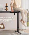 Person sitting on 47.2 Inch Standing Desk With Adjustable Height And Wood Top For Home Office And Gaming, load capacity 176 lbs.