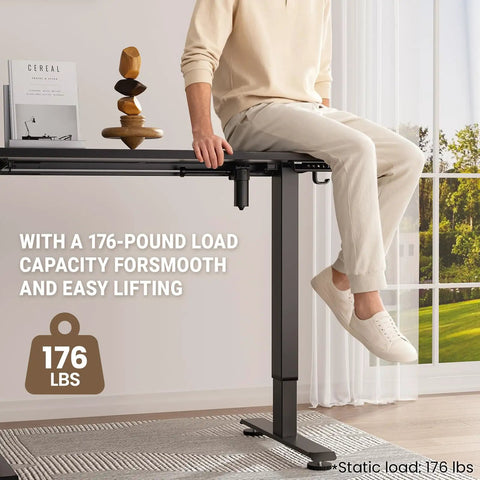 Person sitting on 47.2 Inch Standing Desk With Adjustable Height And Wood Top For Home Office And Gaming, load capacity 176 lbs.