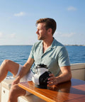 Man holding Two In One Golf Drink Holder Set with a 14oz Insulated Tumbler on a boat table, featuring mini golf bag design.