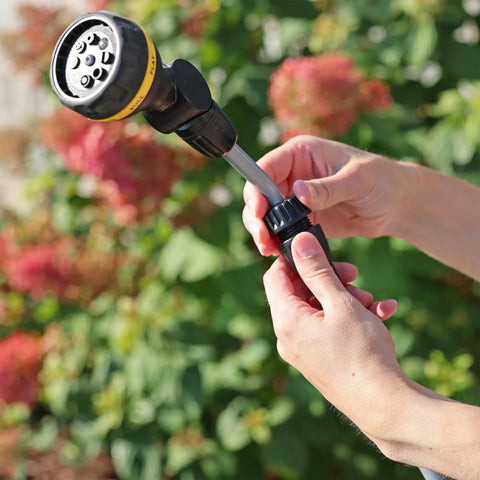 Hands adjusting RelaxGrip No Sweat Eight Pattern Pivoting Head Watering Wand With Quick Connect Extension in garden setting.
