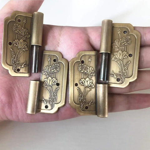 Antique Brass Visible 4 Pack Small Hinges 2x2 Inches For Cabinets And Drawers shown in hand, vintage style with floral design.