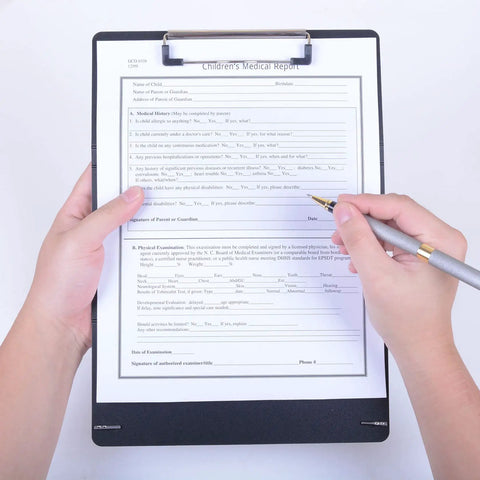 Two Pack Foldable Nursing Clipboard With 3 Layers And Medical Reference Cheat Sheets Lightweight Plastic Black Must Have Nurse Work Essentials For Shifts Portable Clipboard Set For On The Go showing a medical report being filled on a black clipboard with silver clip.