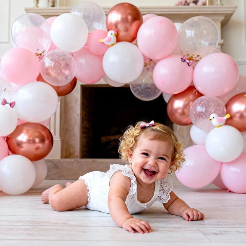 Balloon Arch Stand Kit with pink, white, and rose-gold balloons forming an arch behind a baby on the floor.