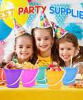 Three kids with party hats smiling behind 12 Pack 5 Inch Beach Buckets and Shovels Set for Kids in colorful shades on a party table.