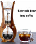 Portable Cold Brew Drip Tower With Smooth Flow Dial And Hefty 1000 Milliliter Pitcher For Chilling Bold Iced Coffee Creations And Nitro Blends While You Kick Back And Enjoy Every Single Cup, shown with iced coffee and wood frame.