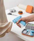 Handheld No Sew Clothing Repair Tool With Seven Color Fasteners in use on a silk garment hem for quick repairs.