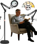 Large Floor Magnifying Glass With Light And Stand beside a man reading, adjustable height, 30X and 12X zoom, black color.