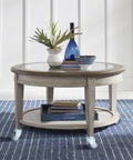 Round glass-top coffee table on four swivel caster wheels with a light gray wood frame.