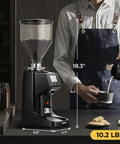 Straight Up Pro Level Electric Coffee Grinder With Industrial Flat Steel Burrs 19 Adjustable Grinding Settings Digital Timer Lock And Huge Thirty Five Ounce Hopper next to a barista pouring milk