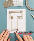 Hands assembling 60 Piece White LED Circuit Stickers and Conductive Fabric Tape DIY Light Kit For Crafters on blue background