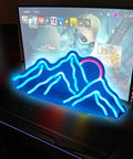Blue mountain range neon sign on desk with pink sun, LED design for wall decor, perfect for gaming rooms and party vibe.