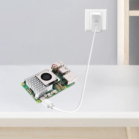 Raspberry Pi 5 Starter Kit With 4GB RAM, 27W PD Power Supply, Active Cooler on a table with USB-C cable plugged in