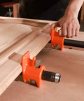 PONY wood gluing pipe clamp fixtures, side view: two orange clamps on a black 3/4-inch pipe securing a wooden panel