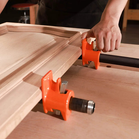 PONY wood gluing pipe clamp fixtures, side view: two orange clamps on a black 3/4-inch pipe securing a wooden panel