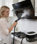 User cleaning kitchen hood with Supercharged Portable Handheld Steam Cleaner With Lightning Fast Fifteen Second Heat Up.