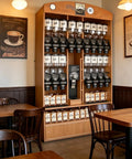 Beefy Heavy Duty Countertop Coffee Bean Dispenser Set 6 Liters large acrylic jars in a cafe setting with tables.