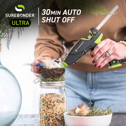 Person using Auto Shut Off Hot Glue Gun Dual Temperature Full Size 60W for crafting, visible with jar and bird nest.