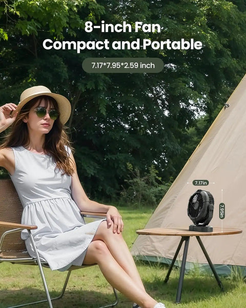 Portable Camping Fan With LED Lantern, 360 Degree Rotating Head on a table beside a tent, woman seated nearby.