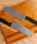 Two-piece stainless steel potato slicers with crinkle blades and black handles on a wooden cutting board