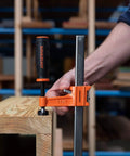 Twelve Inch Steel Bar Clamp With Instant Adjustment And Lightweight Orange Finish One Quarter Inch By Three Quarter Inch Spring Steel Bar Ideal Woodworking Clamp For Quick Grips And Grab And Go Setup on wood board