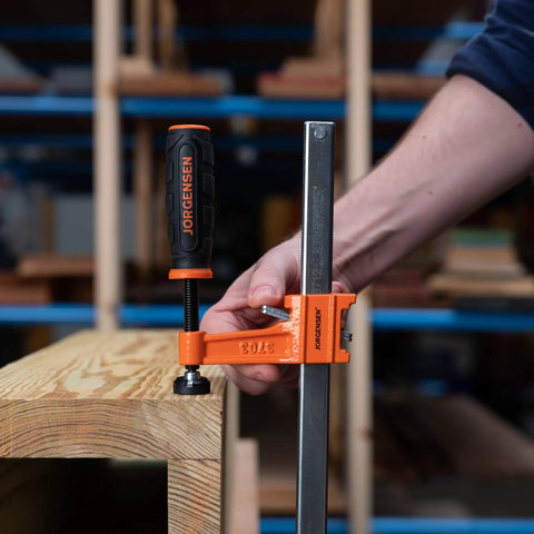 Twelve Inch Steel Bar Clamp With Instant Adjustment And Lightweight Orange Finish One Quarter Inch By Three Quarter Inch Spring Steel Bar Ideal Woodworking Clamp For Quick Grips And Grab And Go Setup on wood board