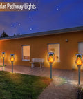 8 Pack Solar Torch Lights With Real Flickering Flame illuminating a walkway by a house, creating a warm nighttime ambiance.