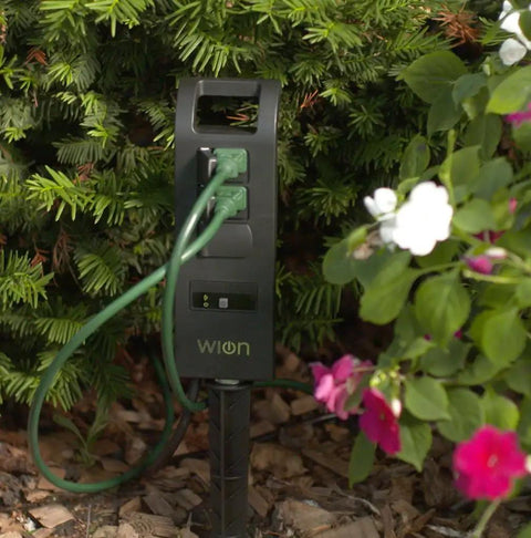 Outdoors WiFi Smart Yard Stake Plug With Three Weatherproof Outlets And Six Foot Cord Straight Up Easy Smartphone Control For Landscape Lighting And Patio Setup Totally Hub Free, positioned among garden plants.