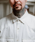 Person wearing a white button-up shirt with visible neck tattoos.