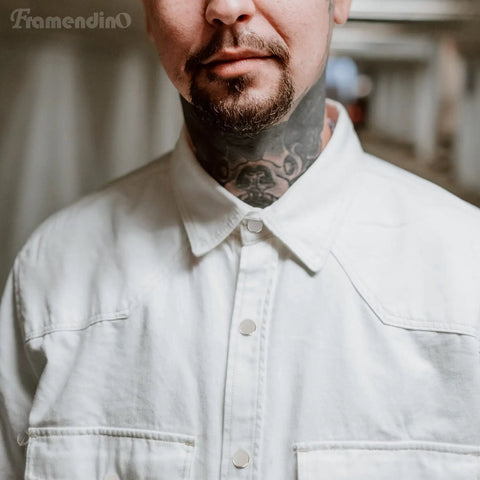 Person wearing a white button-up shirt with visible neck tattoos.