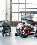 Two mechanics working on vehicle in garage with tool cart and 8 Pack Magnetic Spray Can Holders Wall Mounted Set For Garage