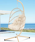 Swing Egg Chair With Stand for Indoor Outdoor Use, beige wicker rattan with UV resistant cushions by the seaside