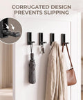 8 Pack Foldable Wall Hooks Matte Black Zinc Alloy mounted on wall displaying keys, umbrella, and jacket for space saving organization