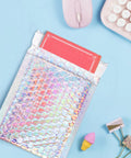 Dope Metallic Bubble Mailers Set, 50 Self Seal Padded Envelopes, Waterproof Holographic Shipping Envelopes on a desk