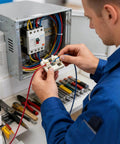 Electrician wiring a control panel with tools on workbench, related to Wireless Adjustable Portable Soldering Jig For Wires And PCBs.