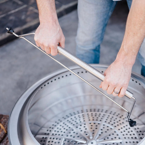 Person using Yukon 27 Inch Fire Pit Handle Accessory Makes Moving Your Fire Pit A One Hand Easy Portable Carry For Camping Outdoors.