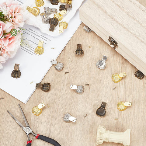 Dope Antique Zinc Alloy Feet Set 30 Pieces In 3 Colors scattered on a wooden table with tools and flowers.