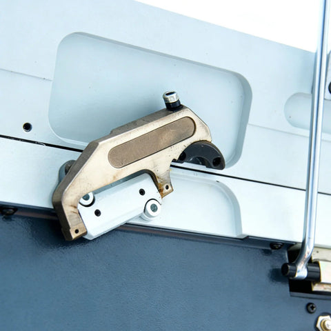 Side view of a brass-colored clamp bar installed on the edge of a sheet metal brake.