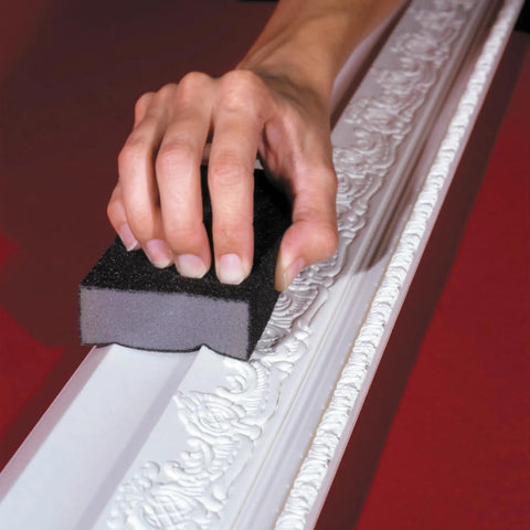 Hand using Pro Grade Sanding Sponges Pack Three By Five By One Inch Medium And Fine Grit for contours on detailed molding surface