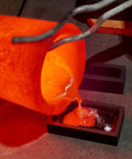 Graphite ingot molds for metal casting; glowing molten orange metal pours into two rectangular molds.